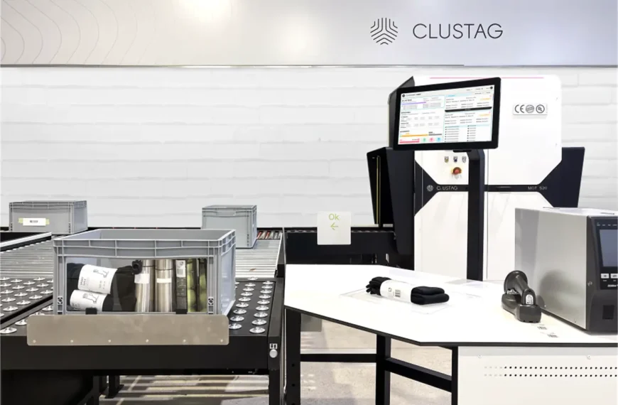 A Clustag RFID audit station setup in a modern warehouse environment, featuring a conveyor belt with plastic bins containing tagged items, a workstation with a large touchscreen displaying Zentup Workflow software, and various RFID devices and printers arranged on a white table.