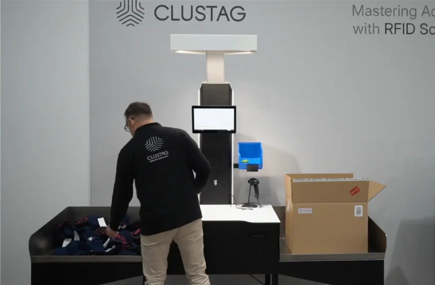 Person using a Clustag RFID system for order management, with a cardboard box on the table and a touchscreen display in the foreground.